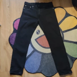 Svarta jeansbyxor från levi's - Snygga svarta jeansbyxor med klassisk design och fem fickor. De har en rak passform och är perfekta för en stilren look. Byxorna har en knapp och dragkedja framtill.