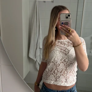 Vit spetsblus från KappAhl - Säljer en söt vit spetsblus från KappAhl i storlek XS. Blusen är kortärmad och har ett vackert spetsmönster som ger en romantisk känsla. Perfekt för att piffa upp vilken outfit som helst!