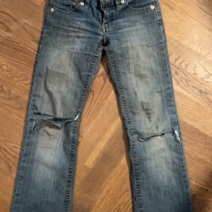 Blå jeans med slitningar - Supersnygga jeans från en gammal kollektion med Kappahl och Girlsgirls. Slitningar vid knäna men de köptes så. BOOTCUT/FLARE och väldigt lowwaist 