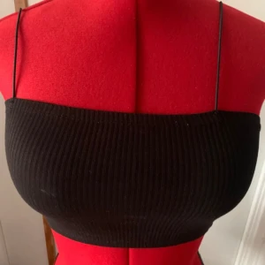 Svart ribbad tubtopp - Snygg svart ribbad tubtopp från H&M med smala axelband. Perfekt för en stilren look.