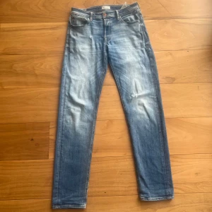 Blå jeans från Jack & Jones - Snygga blå jeans från Jack & Jones med en klassisk straight fit. De har en snygg slitning på framsidan och en liten reva vid fickan för en cool, avslappnad look. Perfekta för en casual stil.