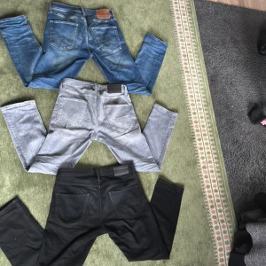 Tre par jeans i olika färger - Säljer tre par jeans i olika färger. Ett par blå jeans med klassisk design, ett par grå jeans och ett par svarta jeans. Perfekta för olika tillfällen och stilar. Blå= W29 L32/ Grå= W29 L30 svart= W30 L30