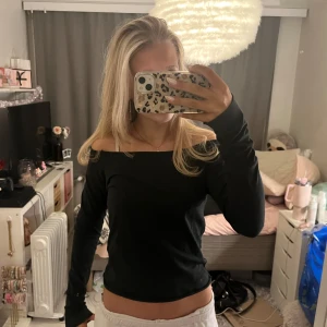Svart offshoulder brandymelville topp - Snygg svart offshoulder topp med långa ärmar. Perfekt för en stilren look och kan matchas med både jeans och kjol. Enkelt och elegant val för olika tillfällen.