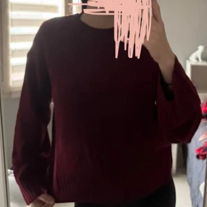 Vinröd stickad tröja - Säljer en mysig vinröd stickad tröja med långa ärmar. Perfekt för kyliga dagar och passar bra till både jeans och kjol. Tröjan har en enkel design med rund hals och ribbade muddar.