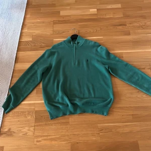 Grön Ralph lauren tröja med dragkedja - Snygg grön tröja med halv dragkedja och ribbade muddar. Perfekt för en stilren look. Passar bra till både jeans och chinos.