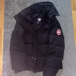 Svart dunjacka från Canada Goose - Svart canada goose jacka i fint skick. En knapp hade gått sönder vilket jag fick fixa hos en skräddare med en ny knapp annars är jackan i fantastiskt skick. PRISET KAN SJÄLVKLART DISKUTERAS