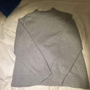 Grå stickad tröja  - Säljer en stilren grå stickad tröja från Jack & Jones.Tröjan är helt oanvänd och jag klippte av lapparna därför hade jag inte möjlighet att lämna tillbaka den.Tröjan har ribbade muddar vid ärmslut och nederkant, vilket ger en snygg och bekväm passform. Perfekt för kyligare dagar!