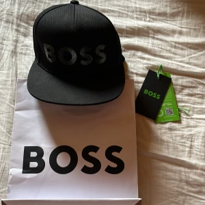 Svart keps från Boss - En riktigt snygg keps från Hugo boss. Kepsen är inte använd alls mycket. Köpte den på NK i GBG. Kepsen är i nytt skick men säljer den för toppen pris.400kr