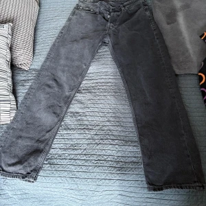 Svarta jeans från Jack & Jones - Säljer ett par svarta jeans från Jack & Jones med relaxed fit. De har en klassisk design med knappar och dragkedja i gylfen. Perfekta för en avslappnad stil.