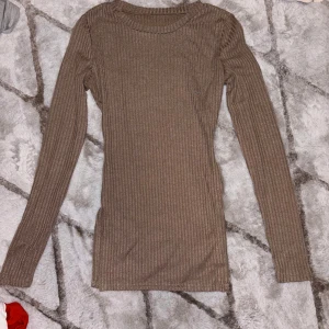 Beige långärmad tröja med spetsdetaljer - Säljer en stilren beige tröja med v-ringning och spetsdetaljer längs halsringningen. Tröjan har långa ärmar och är perfekt för en elegant look. Passar bra till både jeans och kjol. Första tröjan är öppen på sidorna i storlek S. Andra storlek M.