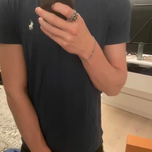 Mörkblå t-shirt från Ralph Lauren - Säljer en stilren mörkblå t-shirt från Ralph Lauren med det klassiska broderade logotypen på bröstet. Perfekt för en avslappnad och snygg look. T-shirten är kortärmad och gjord i mjukt material.