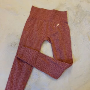 Rosa träningstights - Säljer ett par träningstights från Gymshark, storlek XS. Tyvärr ett hål i ena sidan innerben men annars bra skick. Säljer för 100kr + frakt