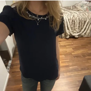 Mörkblå blus från Loren - Säljer en elegant mörkblå blus med korta ärmar och ett vackert broderat mönster vid halsringningen. Perfekt för en stilren look.