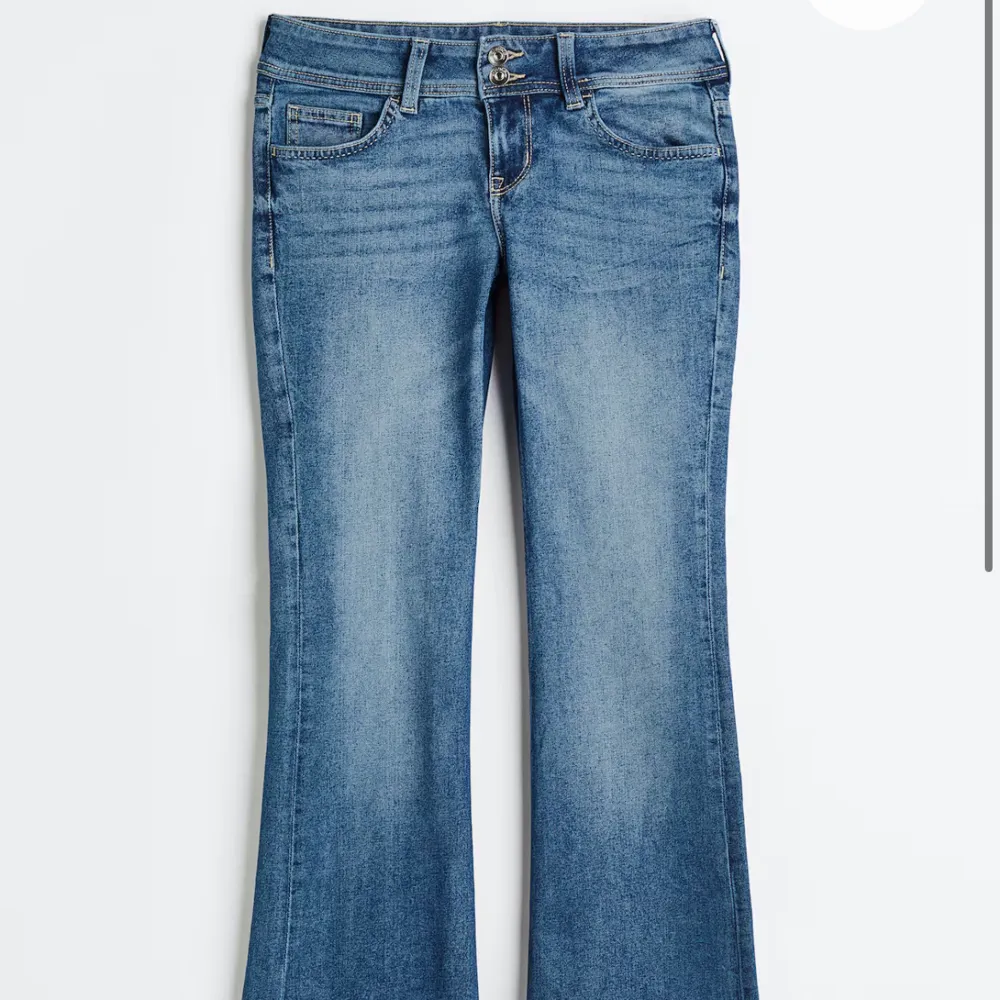 Snygga populära och slutsålda blå bootcut jeans från Hm med klassisk femficksdesign och knappdetalj på bakfickan. Perfekta för en avslappnad stil med en touch av retro. De har en bekväm passform och är tillverkade i slitstarkt denim.. Farkut & Housut.
