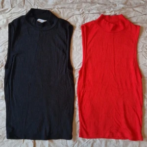 Svart och röd ribbad ärmlös topp - Två snygga ribbade ärmlösa toppar i svart och rött. Perfekta för lager-på-lager eller att bära som de är. De har en hög krage som ger en stilren look.