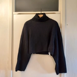 Svart ribbad polotröja från BikBok - Snygg svart ribbad polotröja från BikBok i croppad modell. St S men har en oversized passform. Perfekt för kyliga dagar med sin höga krage och långa ärmar. Tröjan har en modern och stilren design som passar till många olika outfits.