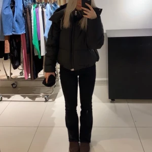 Svart pufferjacka med dragkedja - Säljer en svart pufferjacka med dragkedja och hög krage. Jackan har en modern och bekväm passform, perfekt för kyligare dagar. Den är stilren och lätt att matcha med olika outfits.
