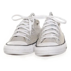 Grå sneakers från Converse - Snygga grå Converse sneakers med klassisk design och vita snören. Skorna har en låg profil och är perfekta för en avslappnad stil. De har en vit sula med svart rand och Converse All Star-logga på hälen.