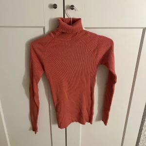 Mörkrosa  ribbad polotröja - Säljer en snygg mörkrosa ribbad polotröja med långa ärmar. Perfekt för kyligare dagar och ger en stilren look. Passar bra till både jeans och kjol. Hör av dig vid intresse!