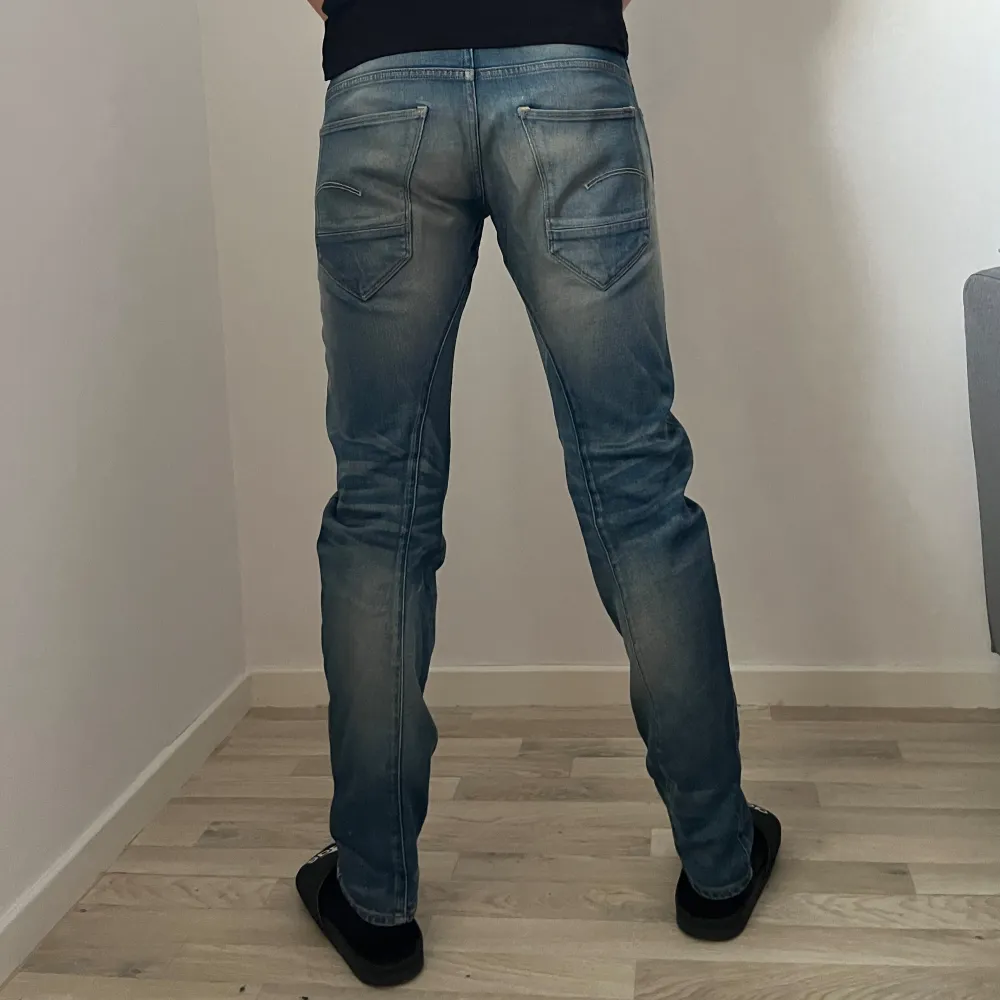 Snygga blå jeans från G-Star RAW med slim passform. Passar en xs-s beroende på hur man vill att de ska sitta. De har en klassisk femficksdesign och knappar i gylfen. W27 L32. Bilderna är tagna med blixt. Farkut & Housut.