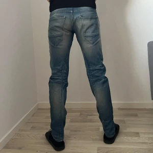 Blå jeans från G-Star RAW - Snygga blå jeans från G-Star RAW med slim passform. Passar en xs-s beroende på hur man vill att de ska sitta. De har en klassisk femficksdesign och knappar i gylfen. W27 L32. Bilderna är tagna med blixt