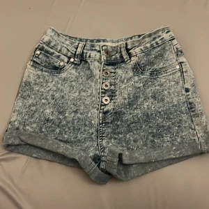 Acid wash shorts från F3 Sista - Snygga acid wash shorts från F3 Sista i en cool blå nyans. De har en hög midja och knappar framtill för en trendig look. Perfekta för sommarens alla äventyr!