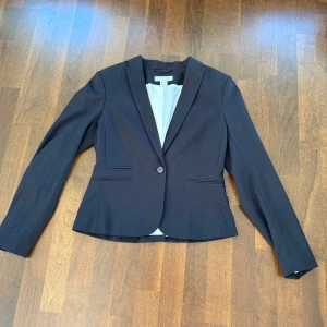Svart kavaj från H&M - Snygg svart kavaj från H&M i storlek 38. Kavajen har en klassisk design med en knapp framtill och långa ärmar. Perfekt för en stilren look. Super bra skick 