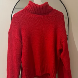 Röd stickad polotröja - Säljer en snygg röd stickad polotröja med ribbad krage och muddar. Perfekt för kyliga dagar och ger en mysig känsla. Passar bra till både jeans och kjol.