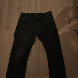 Svarta jeans från Levi's 551, storlek W28 L32 - Säljer ett par svarta Levi's jeans i modell 551. De är i bra skick och har en klassisk straight passform. Perfekta för både vardag och fest. Midjan är midwaist och de har en snygg mörk tvätt. Riktigt bra skick