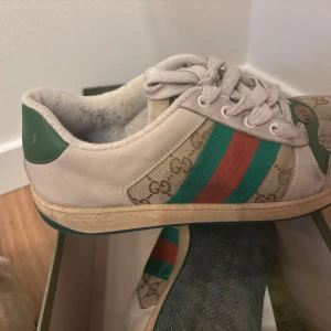 Gucci screeners  - Säljer ett par Gucci sneakers screeners. Skorna har det klassiska Gucci-mönstret och är i bra skick. Perfekta för en stilren och lyxig look. Kommer med originalförpackning och dust bags samt kvitto. Nypris 9000 kr