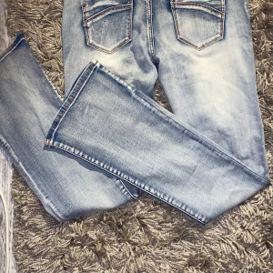 Blå bootcut jeans - Säljer ett par snygga blå jeans från i storlek 42. De har en klassisk femficksdesign och en lätt tvättad look som ger en vintage känsla. De är helt oanvända bara utan prislapp. Mått: rakt över midja: 39cm, Innerbenslängden: 80cm