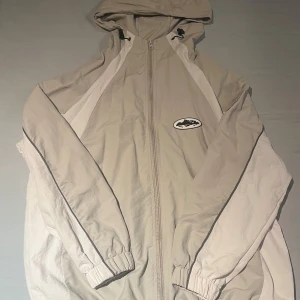 Corteiz windbreaker - En grå corteiz jacka i bra skick, litet hål på ena ärmen men som är täckt med en liten lapp. Storlek S, TTS, lite kort i ärmen. Köpt på Vinted. Skriv privat om du har frågor eller vill ha fler bilder!