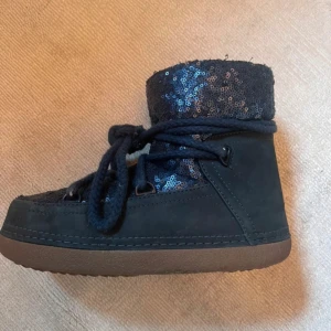 Svarta/mörkblå boots med paljetter från Inuikii - Säljer ett par snygga boots från Inuikii med glittriga paljetter. De har en bekväm brun sula och snörning framtill. Supervarma och Perfekta nu inför vintern ! 🖤 använda en vinter, har lite slitage i ena skon men ingen som syns eller känns. Köpta för lite över 3000 och säljer inte för mindre än 1500 kr 