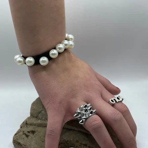 Pärlarmband och silverring - Snyggt pärlarmband med stora vita pärlor på en elastisk tråd, perfekt för att ge en elegant touch till din outfit. Ringen är i silver med en cool, edgy design av små pyramider och bokstäver. Perfekt kombo för både vardag och fest!,jag säljer båda mina ringar,en ring är från Edblad och andra från L8💞🥰man får båda för tusen,ringen från l8 ligger på tusen kronor och Edblad 400kr så man får båda tsm