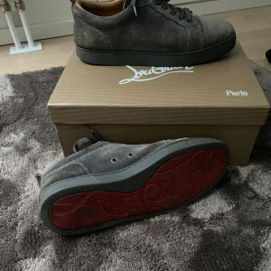 Grå mocka sneakers från Christian Louboutin - Säljer ett par snygga grå sneakers i mocka från Christian Louboutin. De har den ikoniska röda sulan och är i mycket bra skick. Perfekta för både vardag och fest! Skorna har snörning och en stilren design som passar till det mesta. Kvitto finns! För mer bilder kontakta mig! Allt og ingår 