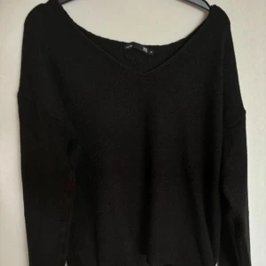 Svart stickad tröja - Mysig svart stickad tröja i damstorlek M. Perfekt för kyliga höst- och vinterdagar. Tröjan har en v-ringad hals och långa ärmar, vilket gör den både stilren och bekväm. Passar bra till både jeans och kjol!