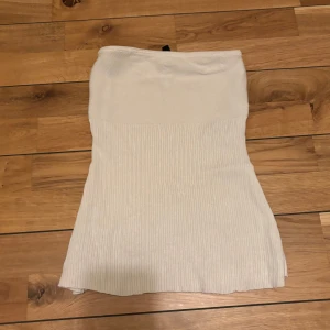 Vit ribbad tubtopp - Säljer en stilren vit ribbad tubtopp i mycket bra skick. Perfekt för sommardagar eller som ett basplagg i garderoben. Den är stretchig och bekväm, vilket gör den lätt att matcha med olika outfits.