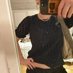 Svart blus med hålmönster - Säljer en snygg svart blus med hålmönster och korta ärmar. 