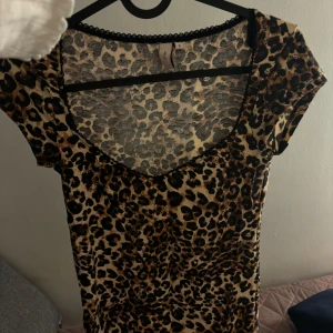 Nelly Leopardmönstrad topp  - Säljer en snygg leopardmönstrad topp med v-ringning. Den är kortärmad och perfekt för en utekväll eller fest. Materialet är mjukt och stretchigt, vilket gör den bekväm att bära. Passar bra till både jeans och kjol för en trendig look.
