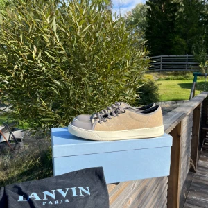 Lanvin sneakers i mocka och skinn - Säljer ett par snygga Lanvin sneakers i beige mocka med grå skinn detaljer. De har en klassisk snörning och en vit sula. Perfekta för både vardag och fest! Skorna är i mycket bra skick och kommer med originalförpackning. De är i storlek 43 passar mellan 42-44, allt tillkommer dust bag och box. Om du har några eventuella frågor är det bara att ställa dom! Mvh Alvin