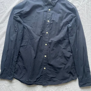 Mörkblå från Selected Homme - Säljer en stilren mörkblå från Selected Homme i storlek L. Skjortan har en slim fit passform och är tillverkad i ett bekvämt material. Perfekt för både vardag och fest! Den har långa ärmar och knappar framtill. Ett måste i garderoben för en klassisk look.