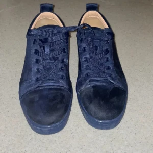 Mörkblå sneakers från Christian Louboutin - Säljer ett par snygga mörkblå sneakers från Christian Louboutin. De är i mycket bra skick och har den ikoniska röda sulan. Skorna är gjorda av mocka och har snörning. Perfekta för både vardag och fest! Kommer med originalkartong och dustbag.pris är ej hugget i sten