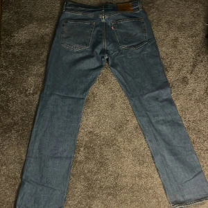 Blå jeans från Levi's - Säljer ett par klassiska blå jeans från Levi's i bra skick. De har en straight passform och är perfekta för vardagsbruk. Jeansen har fem fickor och en knappgylf. Perfekta för både höst och vår!