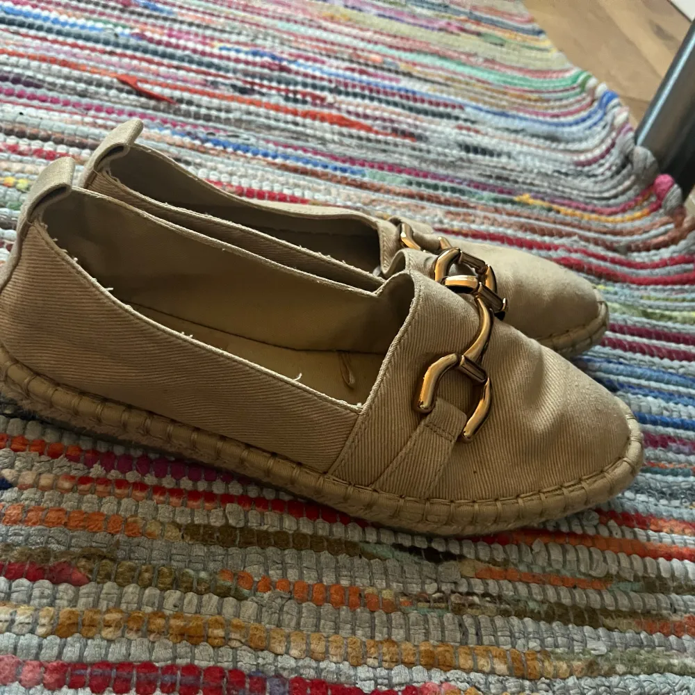 Säljer ett par snygga beige loafers från Zara i bra skick. De har en stilren design med guldfärgade detaljer på ovansidan. Perfekta för vår och sommar, och passar både till vardags och fest. Bekväma och lätta att matcha med olika outfits.. Skor.