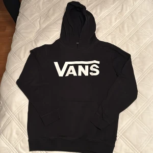 Svart hoodie från Vans - Säljer en svart hoodie från Vans i storlek L (barn) men passar xs.. Den har en stor vit logga på framsidan och är superbekväm med en klassisk känguruficka. Perfekt för både chill och streetwear-stil. 🖤
