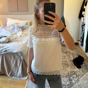 Vit spetsblus med volangdetaljer - Säljer en superfin vit spetsblus med volangdetaljer. Blusen har korta ärmar och ett vackert mönster som ger en romantisk känsla.  Passar både till jeans och kjol för en söt och stilren look.
