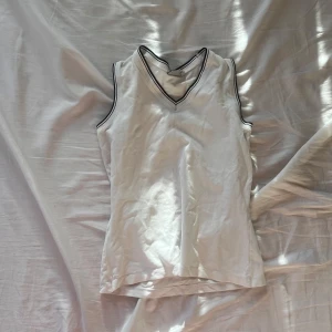 Linne - Säljer en vit och svart  topp från Polarn o pyret. Den har en snygg v-ringning med svarta kantdetaljer som ger en sportig känsla. 