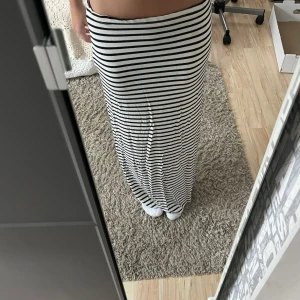Randig långkjol - Säljer en superfin randig långkjol i svart och vit. Perfekt för både vardag och sommarhäng. Kjolen har en skön passform och är gjord i ett mjukt material som faller snyggt. Passar perfekt med en enkel topp eller en stickad tröja för kyligare dagar. Den är tyvärr lite stor i midjan för mig❤️