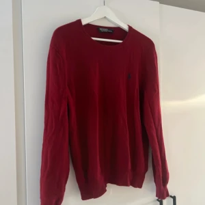 Röd tröja från Polo Ralph Lauren - Säljer en snygg röd tröja från Polo Ralph Lauren. Den är i bra skick och perfekt för höst och vinter. Tröjan har långa ärmar och en klassisk design som passar till det mesta. Perfekt för dig som vill ha något stilrent och bekvämt!