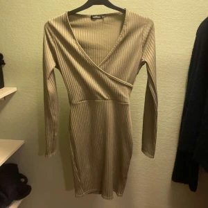 Beige ribbad klänning Boohoo - Säljer en snygg beige ribbad klänning från Boohoo i storlek XS. Klänningen har en omlott-design med v-ringning och långa ärmar. Perfekt för både vardag och fest! 💫 